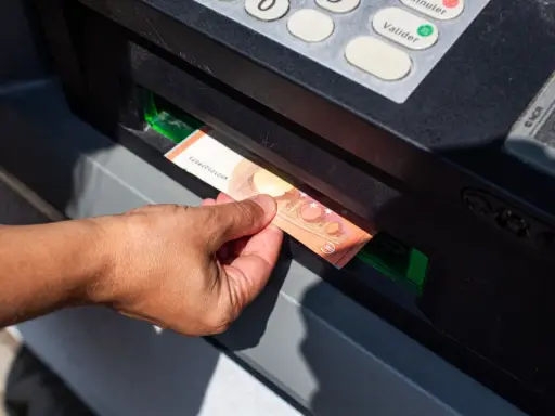 Mano sacando un billete de 50 euros de un cajero automático. La imagen muestra la acción de retirar dinero, lo que nos hace pensar en cuanto dinero se puede sacar del cajero.