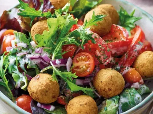 Bunter Salat mit Tomaten, Zwiebeln und Falafelbällchen. Ein schnelles gesundes Essen, das gut aussieht und schmeckt.