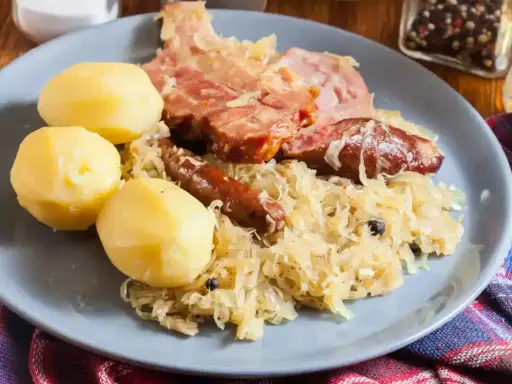 Une assiette de choucroute garnie, avec pommes de terre, saucisses et viande fumée. Un plat qui raconte une histoire culinaire.