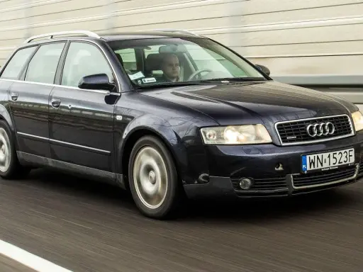 Ciemnogranatowe Audi A4 B6 2.0 Avant pędzi autostradą. Kierowca skupiony na drodze.