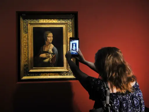 Dama z łasiczką w muzeum, gdzie jest? Kobieta robi zdjęcie słynnego obrazu telefonem.
