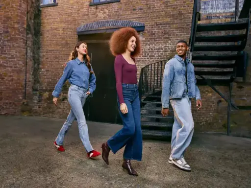 Three friends walk down an alleyway, showcasing how denim is breathable and stylish in various cuts and washes.