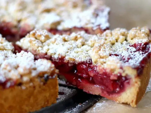 Ein saftiger Kirschstreuselkuchen, bestäubt mit Puderzucker, wartet darauf, genossen zu werden.