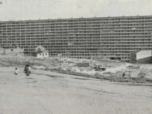 Edificio masivo de apartamentos en construcción, con obreros y vehículos en el sitio. Imagina cómo se veía cuando se inventó el cemento.
