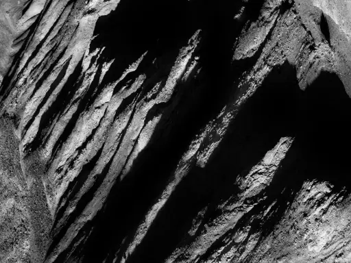 Abstract black and white landscape, reminiscent of Aaron Siskind photos, with dramatic shadows and textured rock formations.