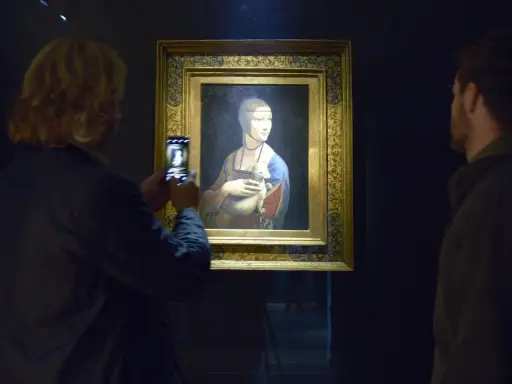Dama z gronostajem Leonarda da Vinci, uwieczniona na zdjęciu przez turystkę. Obok obrazu stoi mężczyzna.