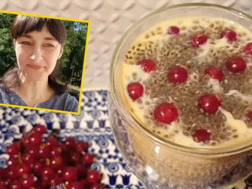 Kobieta uśmiecha się obok deseru z nasionami chia i porzeczkami. Nasiona chia – właściwości odchudzające w pysznej formie.