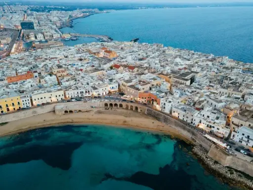 Vista aerea del centro storico di Gallipoli, con case bianche, mare turchese e un arco sul lungomare. Scopri cosa vedere a Gallipoli centro storico.