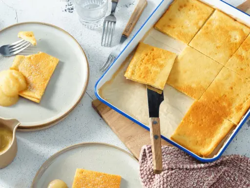 Goldbraune Pfannkuchen vom Blech, frisch aus dem Ofen, werden mit Apfelmus serviert. Ein Genuss für die ganze Familie!