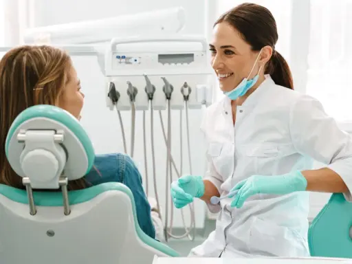 Uśmiechnięta dentystka w rękawiczkach rozmawia z pacjentką. Może właśnie omawia antybiotyk na zęba.