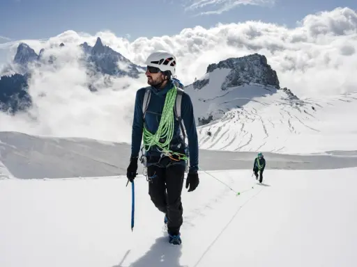 Dwóch alpinistów na ośnieżonym szczycie. Jeden z nich, z czekanem w dłoni, pokazuje, jak dobrać czekan do wspinaczki.