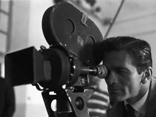 Pier Paolo Pasolini, con lo sguardo concentrato, osserva attraverso l'obiettivo di una cinepresa Arriflex, pronto a catturare la realtà.