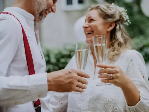 Szczęśliwa para wznosi toast szampanem. To ich piękny ślub po 40. roku życia.