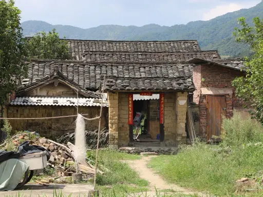 Maison en terre crue, toits de tuiles anciennes, montagnes en arrière-plan. Le prix d'une telle demeure est abordable.