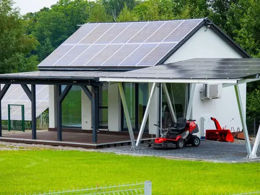 Maison moderne avec implantation panneau solaire sur le toit et le carport. Une tondeuse et un souffleuse à neige sont garés sous le carport.