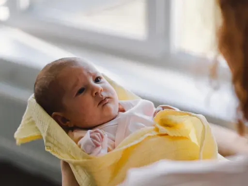 Malutki noworodek pierdzi, ale nie robi kupy. Otulony w żółty kocyk, patrzy z uwagą.
