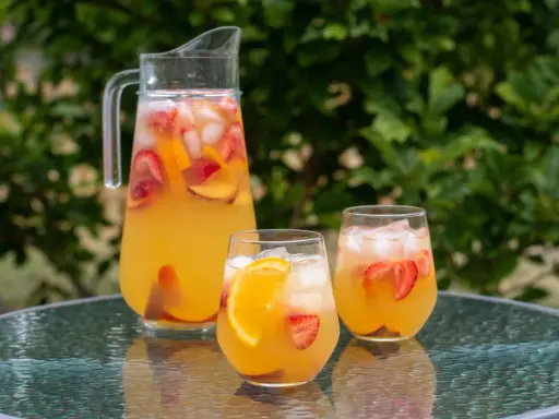 En karaff och två glas med en uppfriskande cava drink fylld med is, jordgubbar och apelsinskivor. Perfekt för en sommardag.