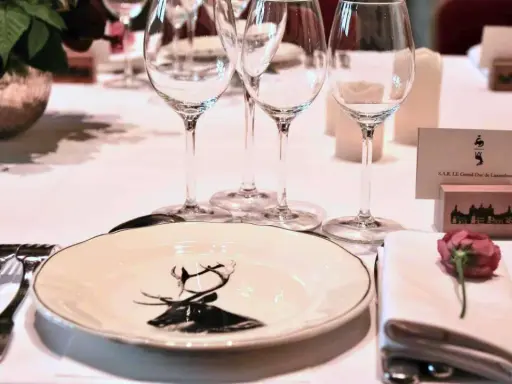 Un élégant dressage à la française pour un dîner de gala, avec une assiette ornée d'un cerf, des verres à pied et une carte de visite pour le Grand-Duc de Luxembourg.