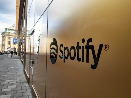 Spotify-logotypen på en guldfärgad fasad. En gata med bilar och människor syns i bakgrunden, vilket antyder att går Spotify med vinst.