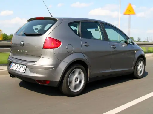 Szary Seat Altea XL jedzie autostradą. W tle widać żółty autobus i znak ostrzegawczy.