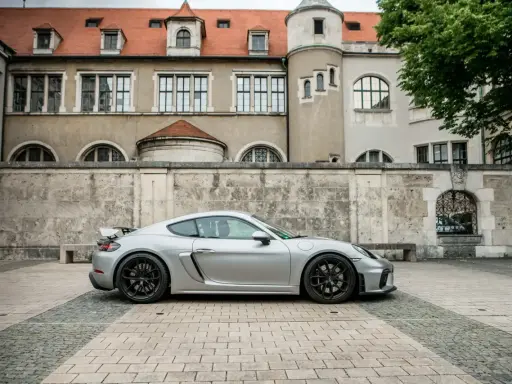 Silberner Porsche GT4 vor historischer Kulisse. Die technischen Daten dieses Sportwagens sind beeindruckend.
