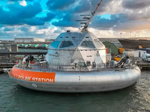 Le bateau Tara Polar Station, une station polaire futuriste, est amarré dans un port sous un ciel dramatique.