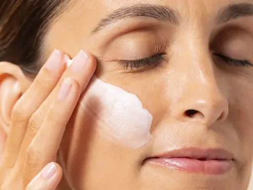 Application d'une crème hydratante contenant de l'acide polyglutamique sur le visage d'une femme.