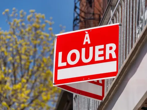 Panneau "À louer" rouge vif, un signe d'espoir pour comment trouver un logement rapidement. Arbre fleuri en arrière-plan.
