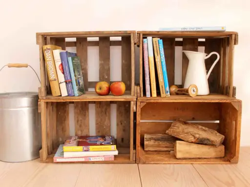 Alte Weinkisten-Ideen: Bücher, Äpfel, eine Kanne und Holzscheite schaffen rustikales Flair.