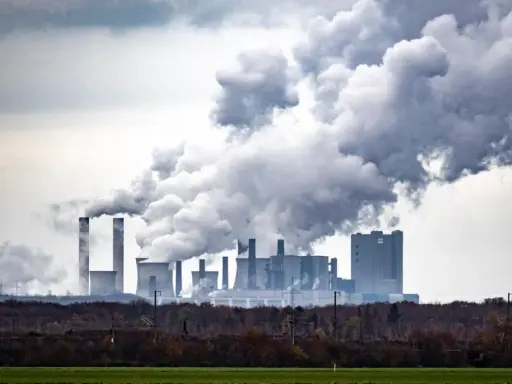Rauchschwaden steigen aus einem Kraftwerk auf und symbolisieren die historischen CO2-Emissionen, die die Umwelt belasten.