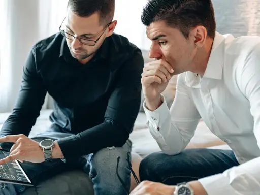 Dos hombres analizan gráficos en una tablet. Uno señala la pantalla, discutiendo cómo domiciliar la nómina para optimizar finanzas.
