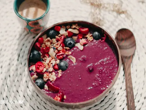 Fruchtige Acai-Bowl mit Blaubeeren, Granola und Beeren – perfekt, wenn du deine eigene Bowl selber machen möchtest. Dazu eine Tasse Kaffee.