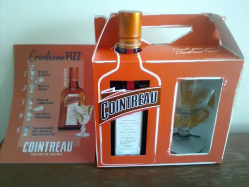 Zestaw Cointreau z kieliszkiem i instrukcją przygotowania drinka Cointreau Fizz. Ten pomarańczowy likier, znany jako Cointreau triple sec, to klucz do orzeźwiających koktajli.