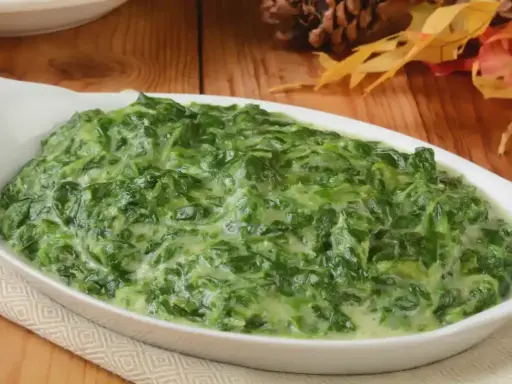 Un plat de épinards à la crème crémeux et appétissant dans un plat blanc, prêt à être dégusté.