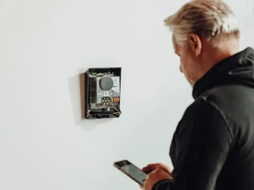 Man med mobil kontrollerar enhet för energisk lastbalansering via wifi.