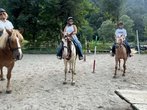 Tre donne si godono una passeggiata a cavallo in Lombardia, con un uomo che le osserva.