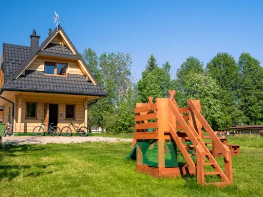 Drewniany domek w Bukowinie Tatrzańskiej z placem zabaw i rowerami przed wejściem. Idealne miejsce na rodzinne wakacje.