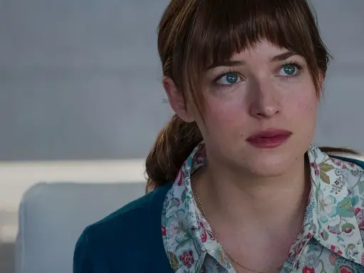 Dakota Johnson med sina blå ögon och blonda hår, klädd i en blommig skjorta och en mörkblå kofta. En scen från filmer med Dakota Johnson.