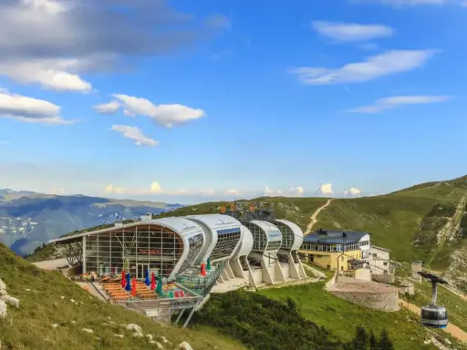 Moderne Seilbahnstation am Monte Baldo mit Panoramablick auf die Berge. Eine Gondel fährt den Hang hinauf.