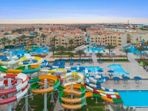 Kolorowe zjeżdżalnie wodne i baseny w Albatros Aqua Park, otoczone palmami i hotelami, zapraszają do zabawy.
