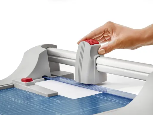 Mano operando una guillotina o cizalla para cortar papel con precisión.