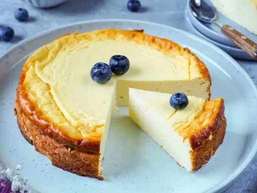 Ein köstlicher low carb Kuchen mit Blaubeeren, der auf einem Teller serviert wird. Ein Stück ist bereits herausgeschnitten.