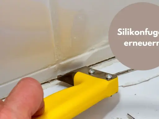 Mit einem gelben Werkzeug werden alte Silikonreste entfernt, um die Fugen zu erneuern.