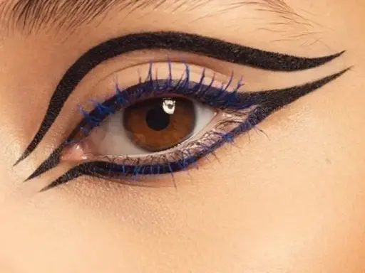 Ojo con delineado dramático y pestañas azules, inspirado en el maquillaje egipcio.