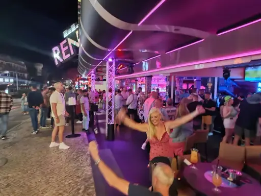 Nachts auf der Albufeira Partymeile: Menschen tanzen und feiern unter Neonlicht in Bars und Clubs.