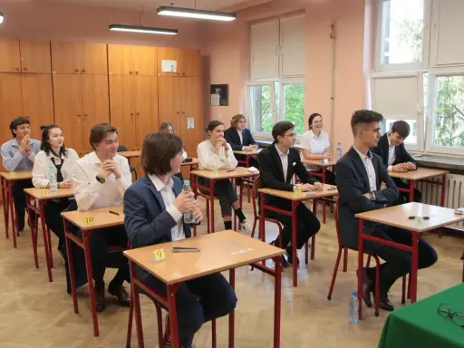Uczniowie siedzą w ławkach podczas egzaminu. Zastanawiają się, ile trwa matura z biologii, skupieni na zadaniach.