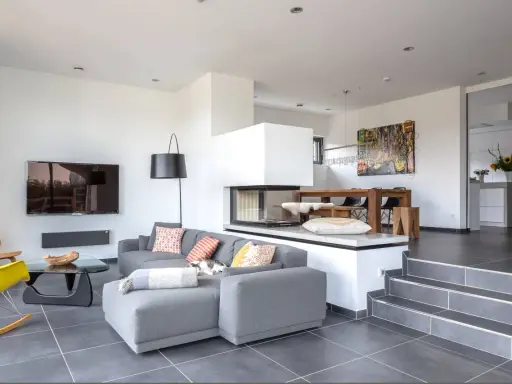 Modernes Split-Level-Haus mit offenem Wohnbereich, Kamin, Essbereich und Küche. Ein Kater döst auf dem Sofa.