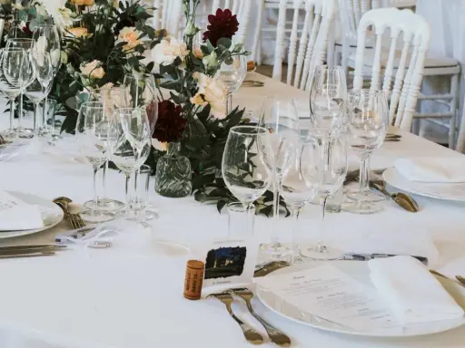 Un élégant dressage d'une table à la française, prêt pour un festin. Verrerie étincelante, fleurs fraîches et menus attendent les convives.
