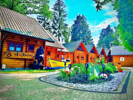 Drewniane domki z psem na tablicy. Wiosna w pełni, kwitnące krzewy i drzewa.