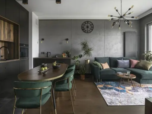 Nowoczesny czarny salon z drewnem, zielona kanapa, owalny stół i designerska lampa.